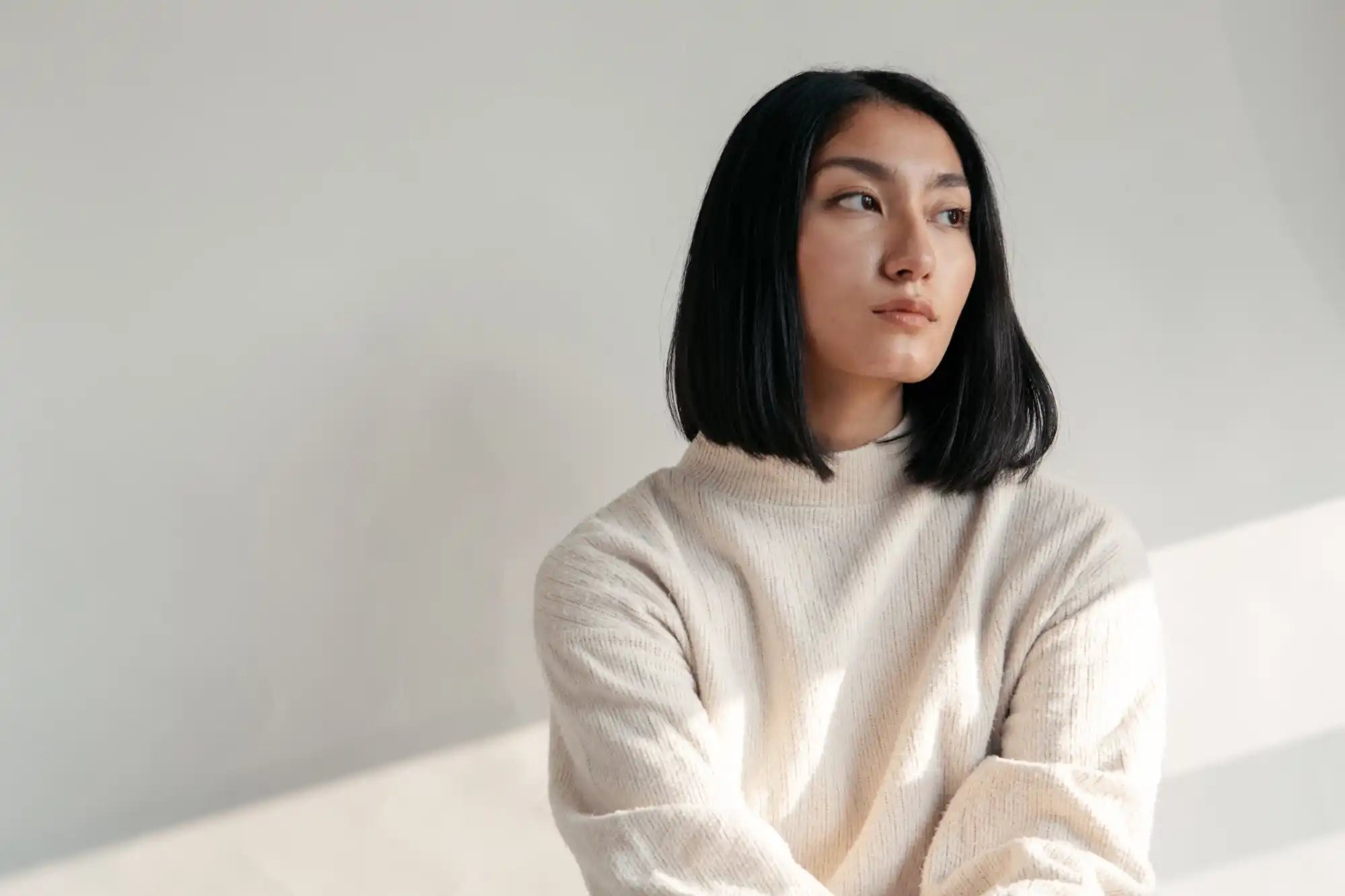 A person wearing a cream-colored sweater gazes upward with a contemplative expression.